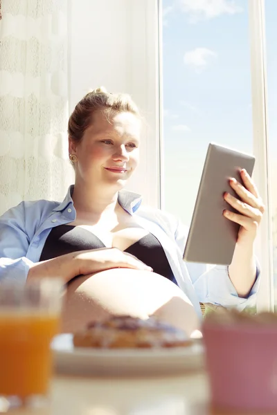 Schwangere lesen oder online einkaufen — Stockfoto