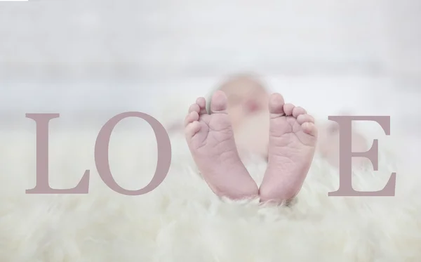 Babyfeet på päls som bildar ordet love — Stockfoto