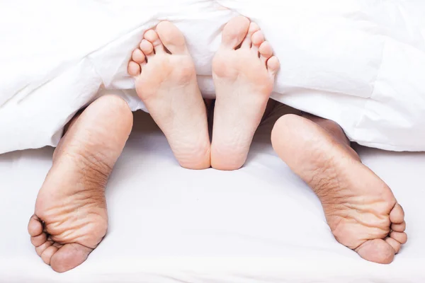 Picioare albe și negre ale cuplului interrasial în pat — Fotografie, imagine de stoc