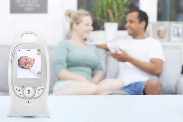 Interracial couple enjoying free time not noticing that their baby is crying on the monitor — Stock Photo, Image