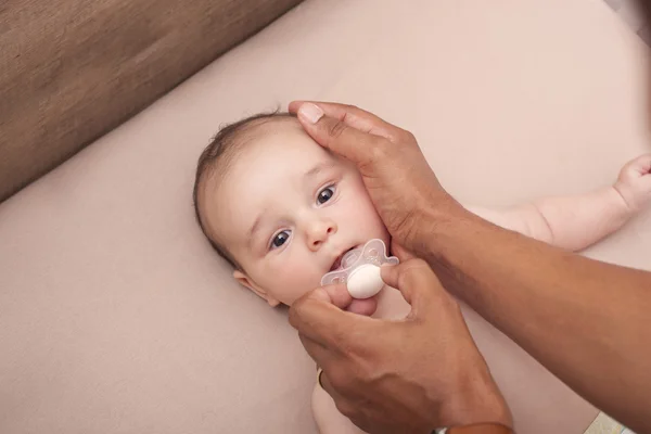 Sex tussen verschillendre rassen vader kalmerende zijn baby met een fopspeen — Stockfoto