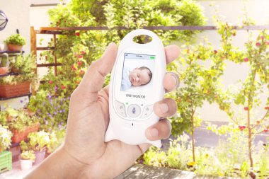 Parent monitoring sleeping baby through baby monitor clipart
