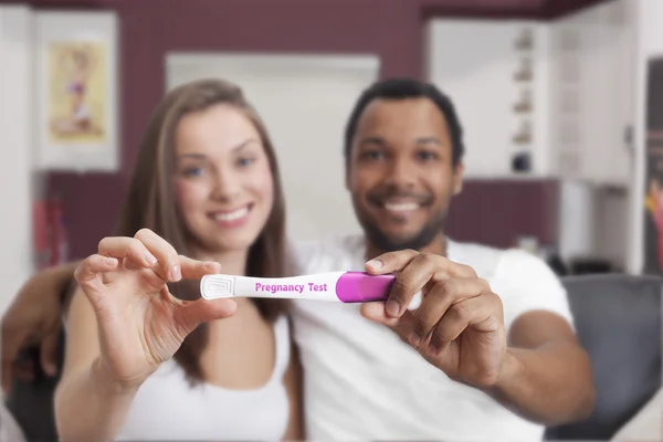 Interracial couple looking at pregnancy test — Stock Photo, Image