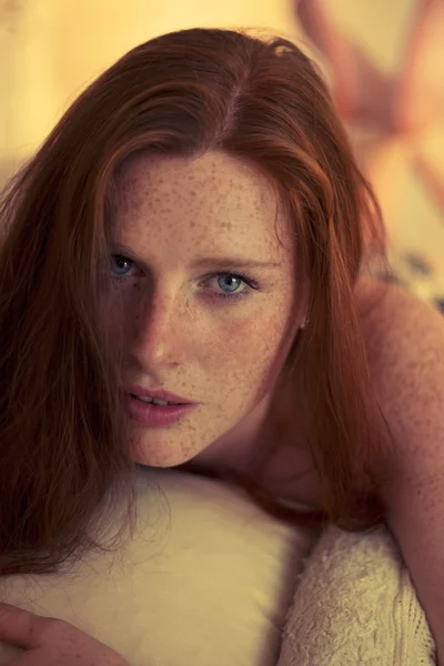 Freckled redhead in a bedroom at Sunset