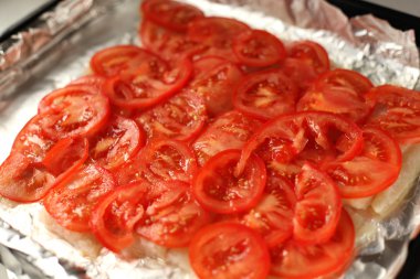 Domates dilimleri altında balık
