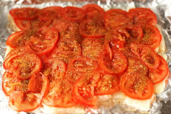 Рыба под томатными ломтиками — стоковое фото