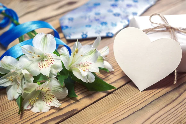 Gift box, flowers, card, ribbon and tie on wooden table