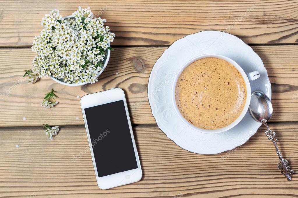 Cup of coffee, mobile phone and flowers on wooden table — Stock Photo