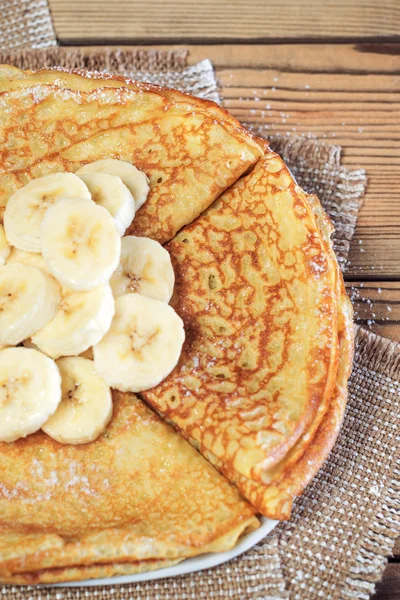 Pannkakor, dammas med strösocker, med en banan. — Stockfoto