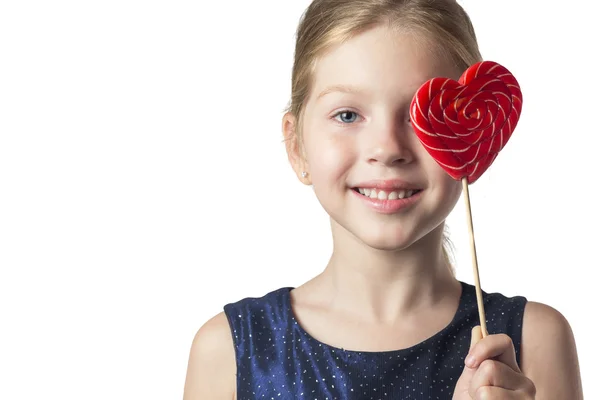 Girl child holding a heart-shaped lollipop . Isolated . — Stock Photo, Image