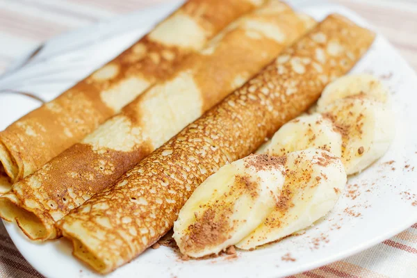 Stekt rullade pannkakorna på ett fat med skivor av banan — Stockfoto