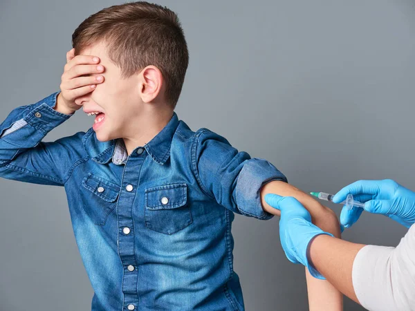かわいい男の子泣いている間にワクチン接種 灰色の背景に隔離された ロイヤリティフリーのストック画像