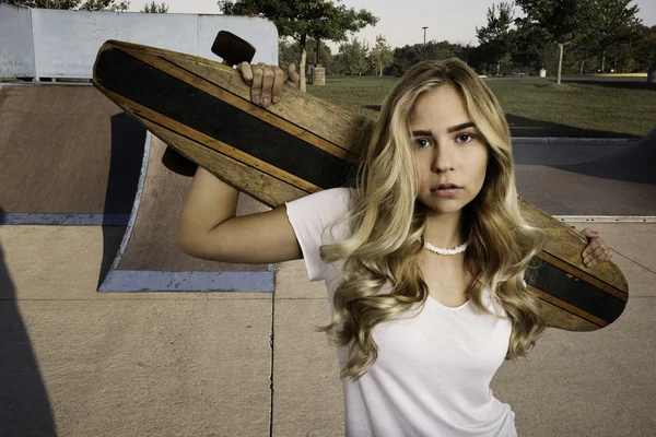 Belle fille blonde debout avec skateboard dans un skate park . — Photo