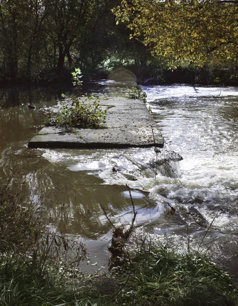 Rivier stroomt over verlaten brug — Stockfoto