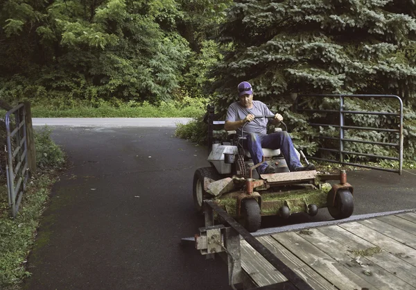 Man loading lawnmower on trailer — Stock Photo, Image