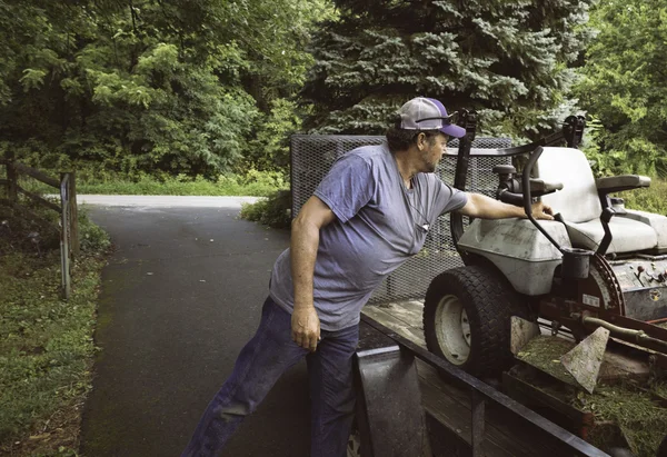 Man loading lawnmower on trailer — Stock Photo, Image