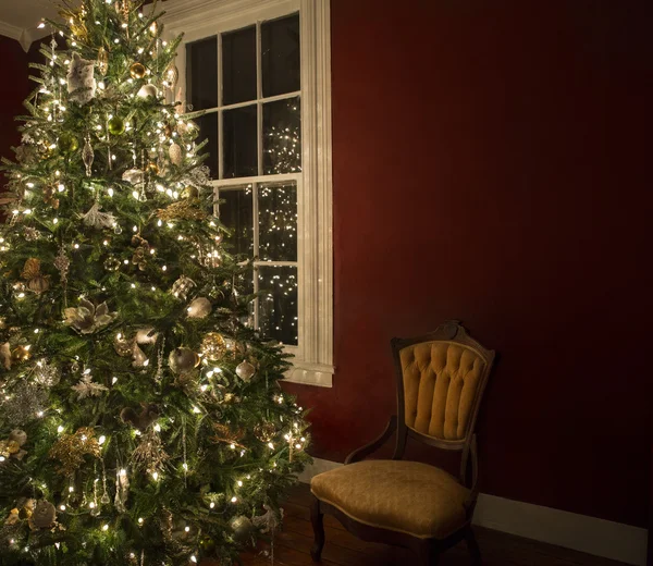 Weihnachtsbaum am Fenster mit leerem Stuhl — Stockfoto