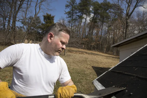 Man taking shingles off a shed roof — Stock Photo, Image