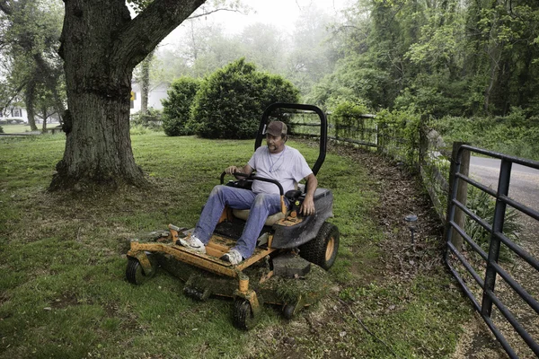 Homem cortando grama no cortador de grama — Fotografia de Stock