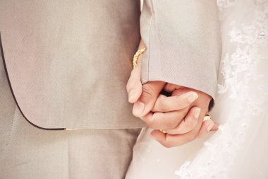 Gelin ve damat el ele tutuşuyorlar.