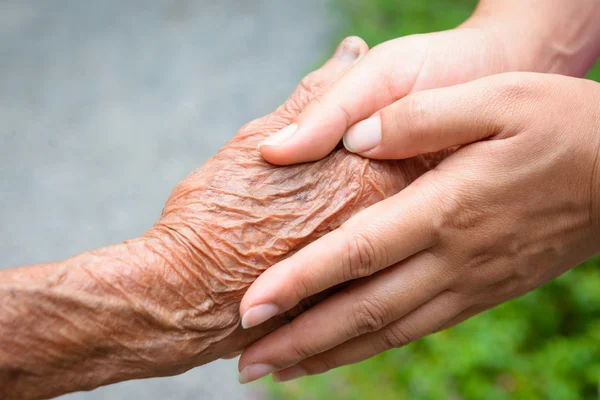 Mayores y jóvenes tomados de la mano — Foto de Stock