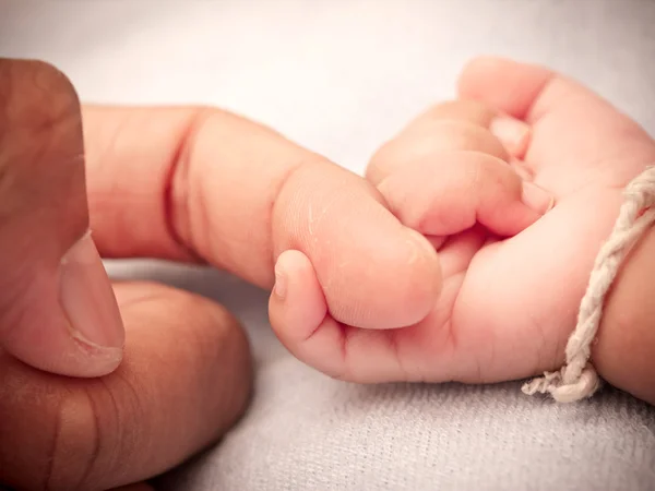 Bebek eli, baba parmağını tutuyor.