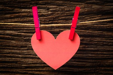 Kırmızı kalp clothesline üzerinde asılı. Eski ahşap arka plan üzerinde.