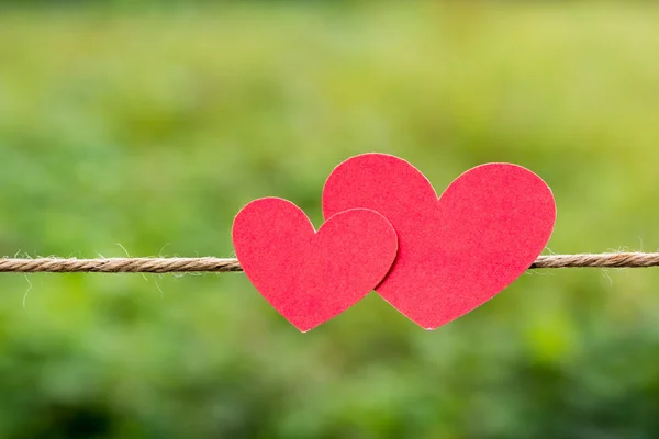 Twee rode papier harten opknoping op de natuurlijke achtergrond. — Stockfoto