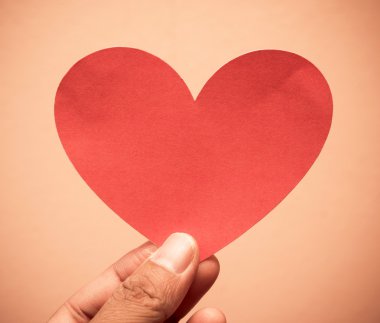 Kırmızı kağıt kalp tutan el.