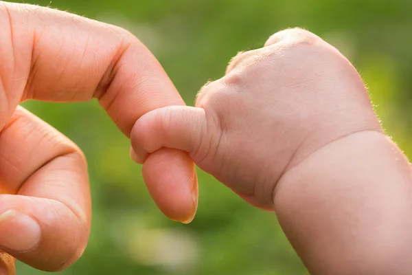 Close-up van moeder en baby's handen. zomer park in achtergrond — Stockfoto