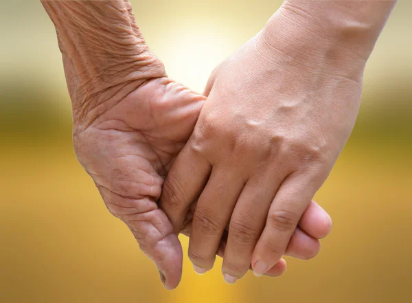 Senior e jovem de mãos dadas ao pôr do sol . — Fotografia de Stock