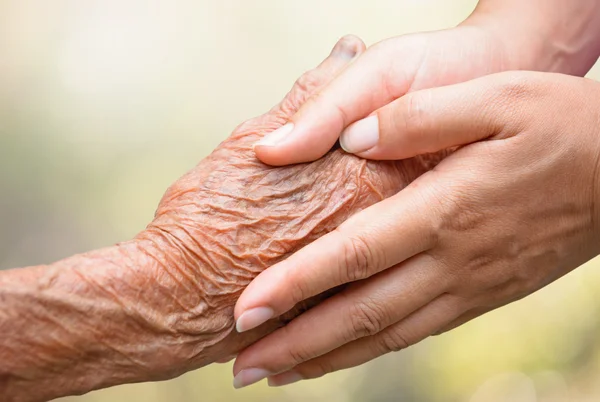 Mayores y jóvenes tomados de la mano — Foto de Stock