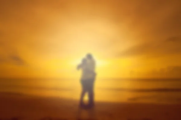 模糊情侣接吻在沙滩上日落的背景 — 图库照片