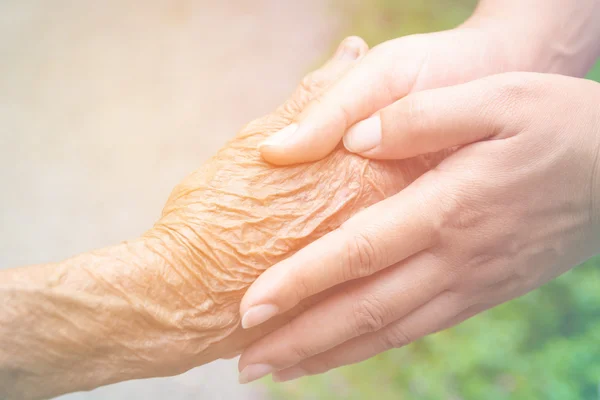 Senior en jongeren hand in hand met vintage kleurtoon — Stockfoto