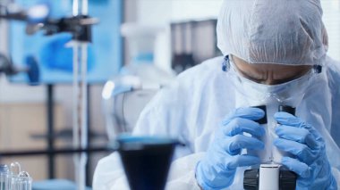 Genç bir doktor laboratuvarda mikroskoba bakar. Genç bir bilim adamı araştırma yapıyor..