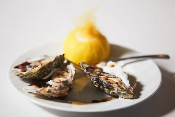 Prato de ostras frescas com molho e limão — Fotografia de Stock