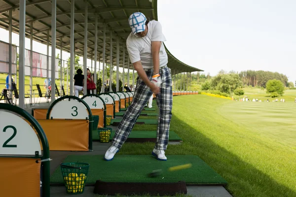Mężczyzna zamiatanie piłki na pole golfowe — Zdjęcie stockowe