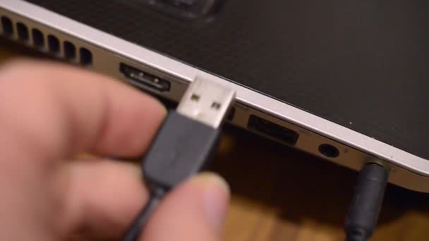 Man takes usb wire into the black notebook. Video closeup. — Stock Video