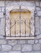 dekoratív kovácsoltvas rács, a fallal körülvett ablak 