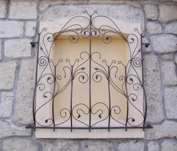 Decorative wrought iron grille on walled window — Stock Photo, Image