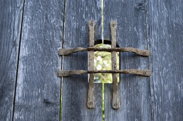 Старая деревянная дверь с металлической сеткой глазок — стоковое фото