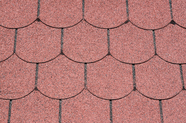 Roof with red bitumen shingles closeup