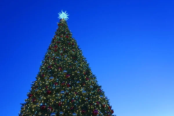 Christmas tree with garlands of glowing and decorations, blue sky —  Fotos de Stock