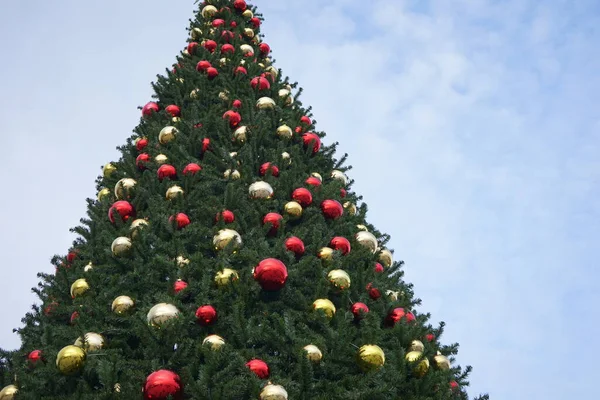 Christmas tree with garlands of glowing and decorations, blue sky — Zdjęcie stockowe