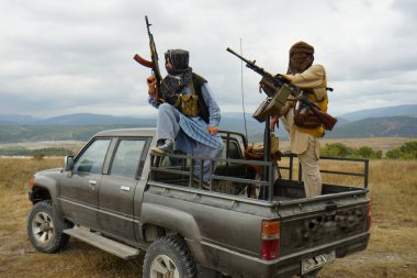 Silahlı teröristler arabadalar, dağların arkasında