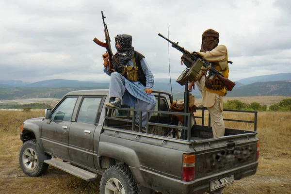 Terroristi armati in macchina, sullo sfondo delle montagne — Foto Stock