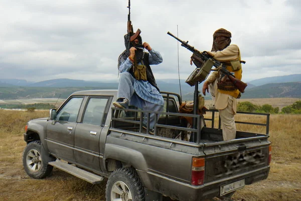 Вооруженные террористы в машине, на фоне гор — стоковое фото