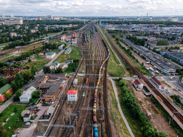Aerial view of railways. Train with cargo moves to terminal. Sorting station. Freight wagons with goods on railroad. Import and export logistics. Industrial landscape. Heavy industry. Drone photo.