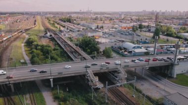 Megalopolis yaşamının havadan görünüşü. Köprüde trafik sıkışık. Platformdan hareket eden yolcuları olan elektrikli tren. Şehirde dolaşmak için farklı yollar. Toplu taşıma mı özel ulaşım mı.