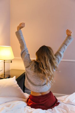 Mutlu kız yatağa otur. Pijamalı, beyaz, tatlı bir kadın sabahları rahatlamak için kollarını uzatıyor. Sabah uyanırsın. Arkadan bak. Bir gün mutlu ve rahat bir uyku çekeceğim..